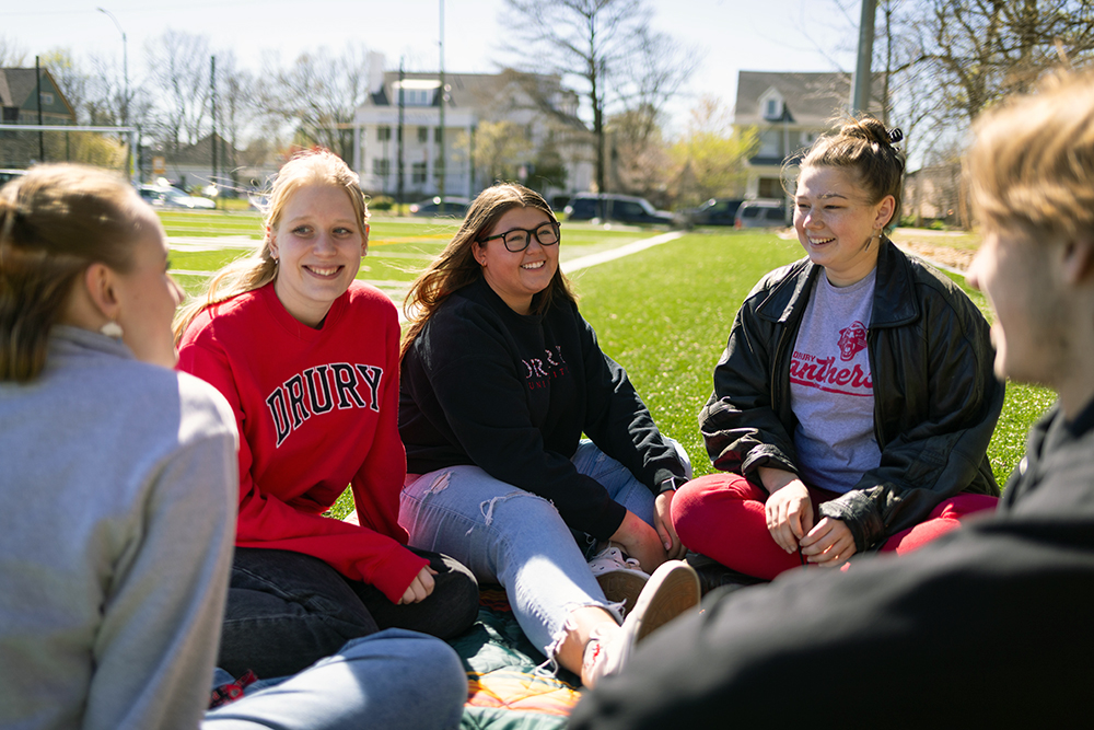A group of students sitting in the grass, who are part of a Living Learning Community at Drury University.