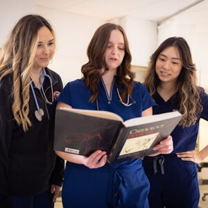 Three PA students reading a medical text.